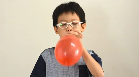 Boy blows up a balloon indoors Stock Footage 48945530