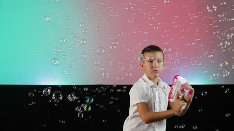 A boy blows a lot of soap bubbles from a gun Stock Footage 341557466