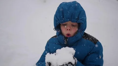 Boy blows snow with hands closeup in slowmo. Snow storm 库存影片 70373979