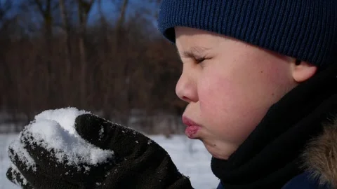 A boy blows on white snow in his hands in winter. The snow is scattering. Stock Footage 314094575