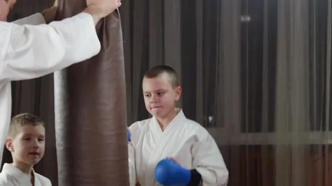 A boy in blue arm pads makes punches on a large hanging machine Video stock 279444501