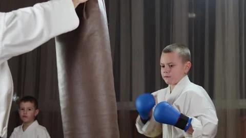 A boy in blue arm pads throws punches on a large hanging machine Stock Footage 279444505