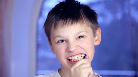 A boy on a blue background brushing his teeth and then chattering teeth Stock Footage 61173783