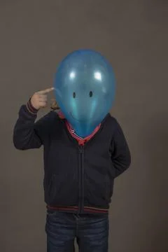 Boy with blue balloon head with happy face and finger pointing hea Stock Photos