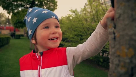 Boy in blue cap examines dry tree and smiles Stock Footage 153559851