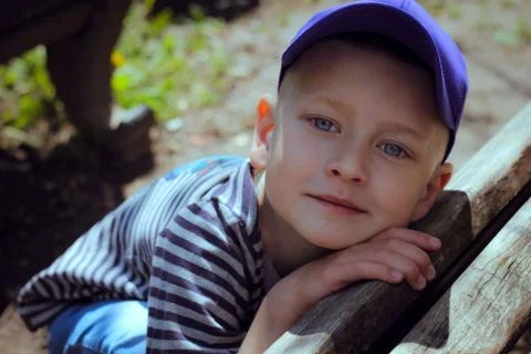 Boy in a blue cap sits at a bench with a traffic light Stock Photos