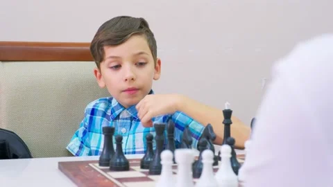 Boy in blue checkered shirt plays chess Stock Footage 209207935