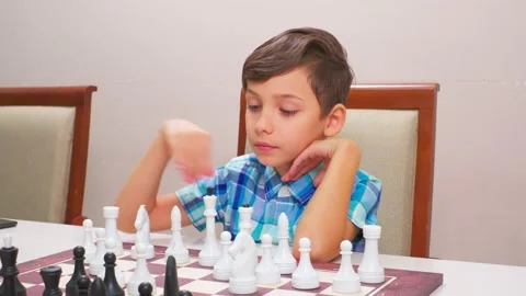 Boy in blue checkered shirt plays chess Stock Footage 209209649