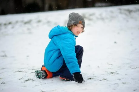 The boy in a blue jacket alone sits on snow. Stock Photos