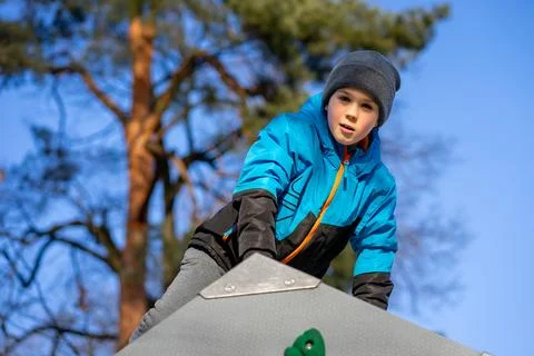 Boy in a blue jacket on a climbing wall, bouldering, active lifestyle Foto stock