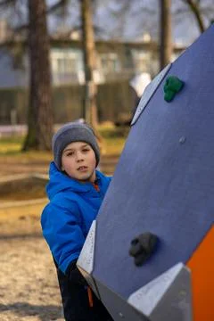 Boy in a blue jacket on a climbing wall, sport climbing, active lifestyle Stock Photos