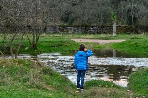 Boy in blue jacket standing by a river Stock Photos