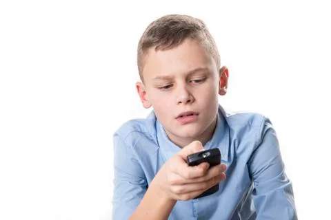 Boy with a blue shirt holds a remote control in his hand and tries to operate Stock Photos