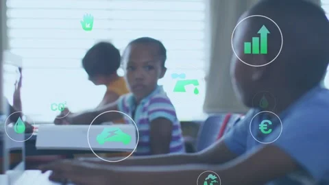 Boy in blue shirt typing computer, causing eco icons moving across class, Stock Footage 332469457