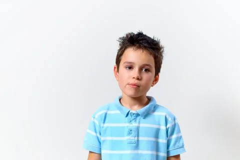A boy in a blue T-shirt with a brooding face looks somewhere from the side. Stock Photos