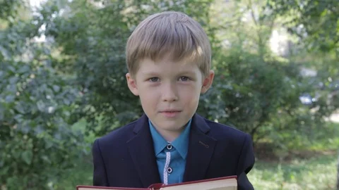A boy with a book in his hands playing his face. The boy looks funny from behind Stock Footage 88806978