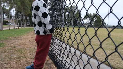 Boy bouncing his back against fence as a repetitive behavior. Vídeos de archivo 295331157