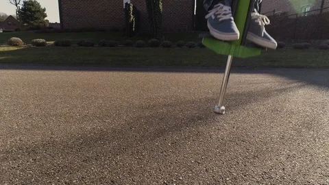 Boy bouncing on a pogo stick Stock Footage 86972774