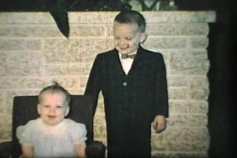 Boy With Bow Tie Kisses Baby Sister (1965 - Vintage 8mm film) Stock Footage 588802