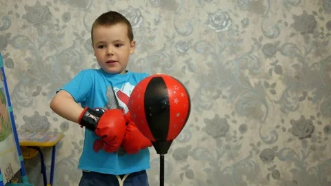 A boy in boxing gloves beats a punching bag Stock Footage 76004437