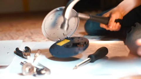 The boy breaks the CD player with a hammer. Video stock 123661574