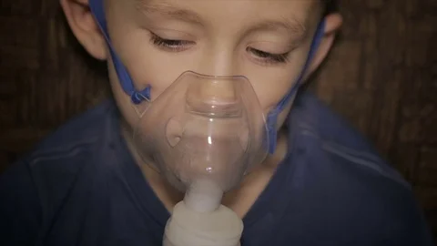 The boy is breathing through the inhaler Stock Footage 71771402