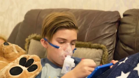Boy breathing through nebulizer at home Stock Footage 145729492