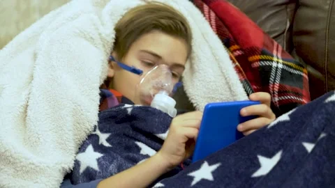 Boy breathing through nebulizer at home Video stock 145729553
