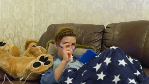 Boy breathing through nebulizer at home Stock Footage 145729569