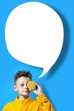 Boy in a bright yellow jacket with a lemon in his hand on a blue background Stockfoto's