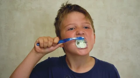 A boy brushes his teeth on a light background Video stock 159160739