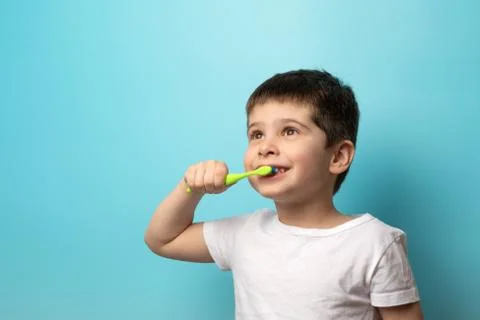 The boy brushes his teeth. A small child with a toothbrush on a blue background Stock Photos