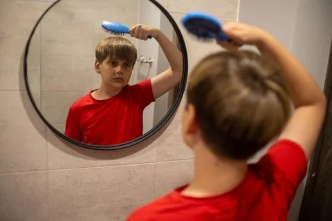 Boy Brushing Hair While Looking In Bathroom Mirror Stock Photos