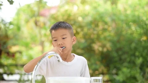 Boy brushing his teeth in the home garden  Stock Footage 70013810