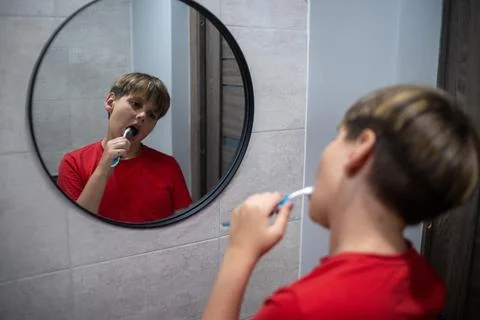 Boy Brushing Teeth In Bathroom With Mirror Reflection Stock Photos