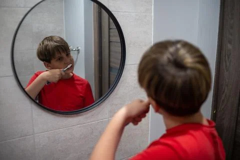 Boy Brushing Teeth In Round Bathroom Mirror Stock Photos