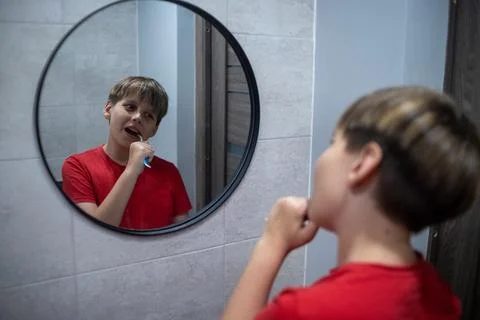 Boy Brushing Teeth While Looking In Round Mirror Stock Photos