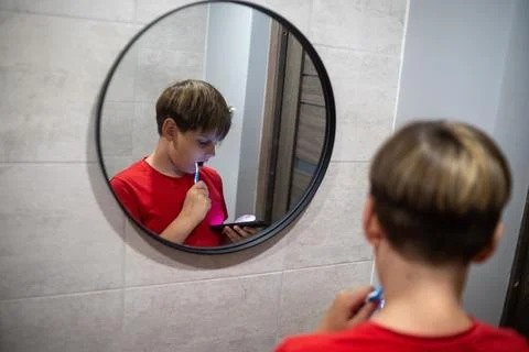 Boy Brushing Teeth While Using Smartphone Mirror Reflection Stock Photos