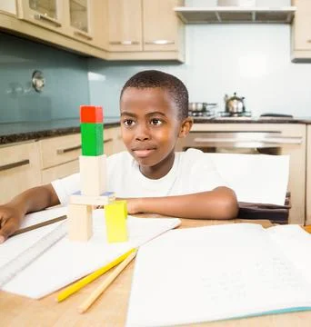Boy building block tower at kitchen table, focusing on creativity and learning Foto stock