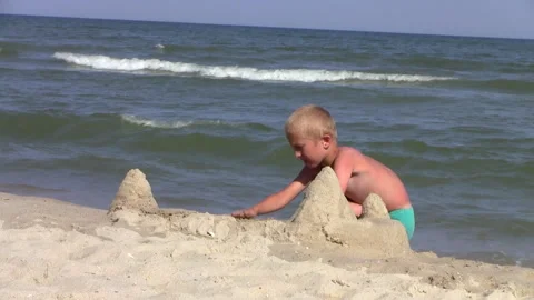 A boy is building a castle on the seashore Stock Footage 236832774