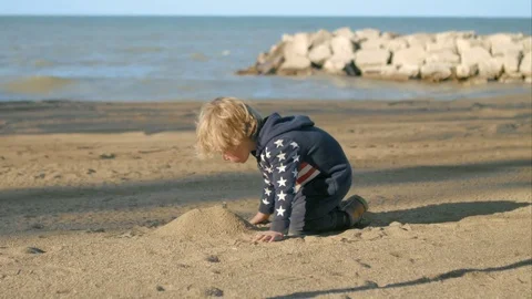 The boy is building a mountain of sand on the beach Video stock 76002088
