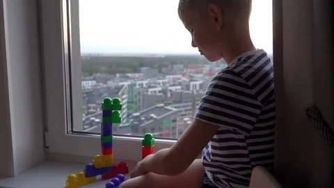 Boy building plastic blocks tower by the window Stock Footage 312011213