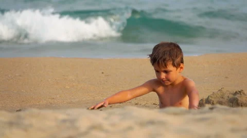 Boy is building a sand castle on the background of the sea waves Vídeos de archivo 128191702