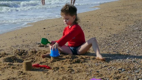 The boy is building a sand castle on the beach Stock Footage 78233563