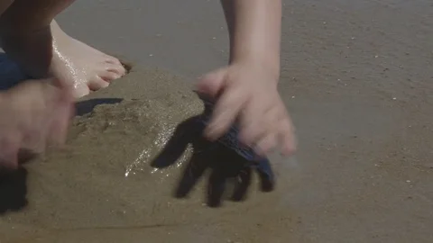 Boy Building Sandcastles with Ocean Waves Crashing on the Beach Stock Footage 74366910