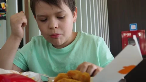 Boy in a cafe eats fast food. junk food. nuggets with sauce. like food. 스톡 동영상 167212488