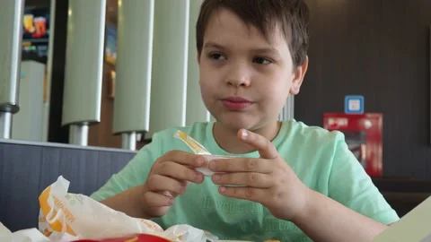 Boy in a cafe eats fast food. junk food. nuggets with sauce. like food. Vídeos de archivo 167212524