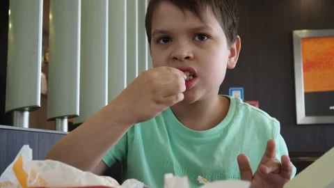 Boy in a cafe eats fast food. junk food. nuggets with sauce. like food. Видео 167212573