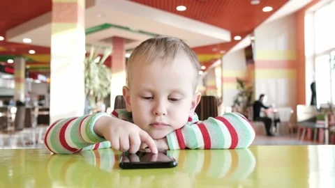 The boy in the cafe uses the phone while waiting for the order Stock Footage 169001777