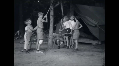 Boy campers playing with rope at campsite Stock Footage